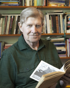 Gary Thomas, headshot. Gary holding a book in front of a bookcase